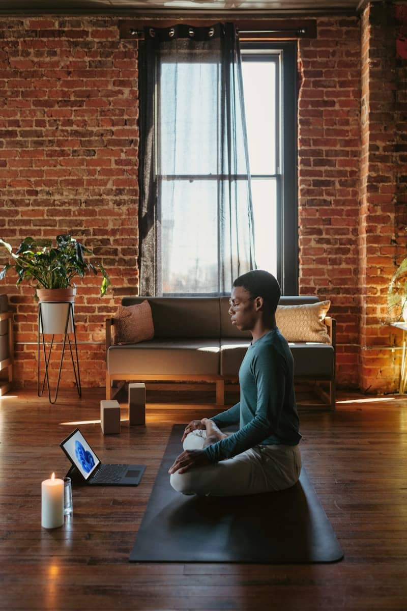 a man sitting on a yoga mat looking at a screen