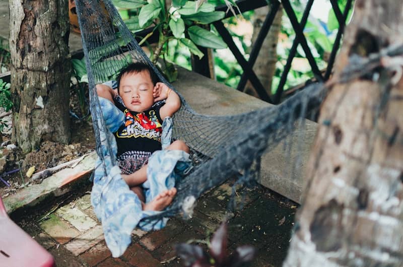 A baby peacefully sleeping in a hammock outdoors