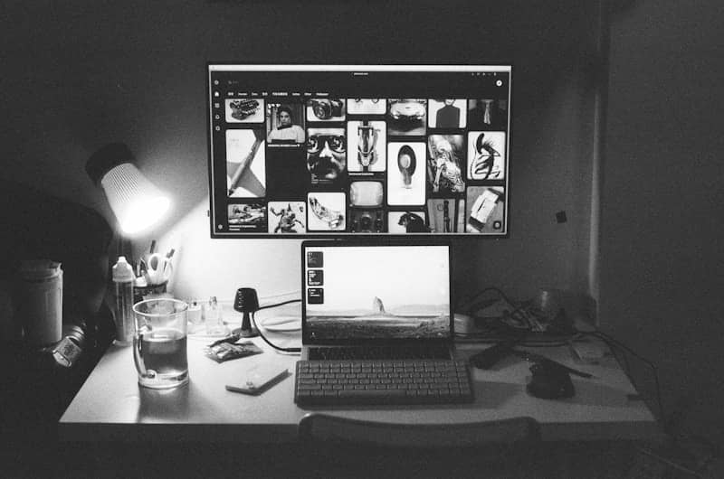 A laptop and monitor display photos on a desk.