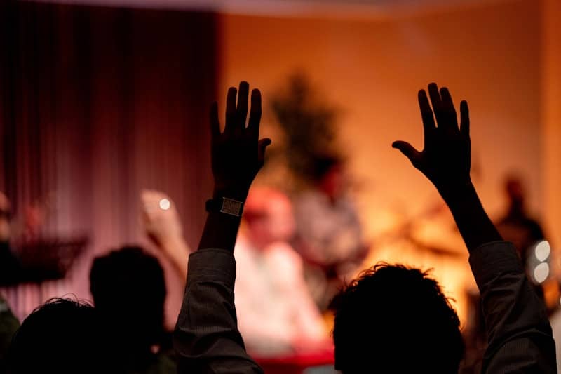 People raising hands in a dimly lit room