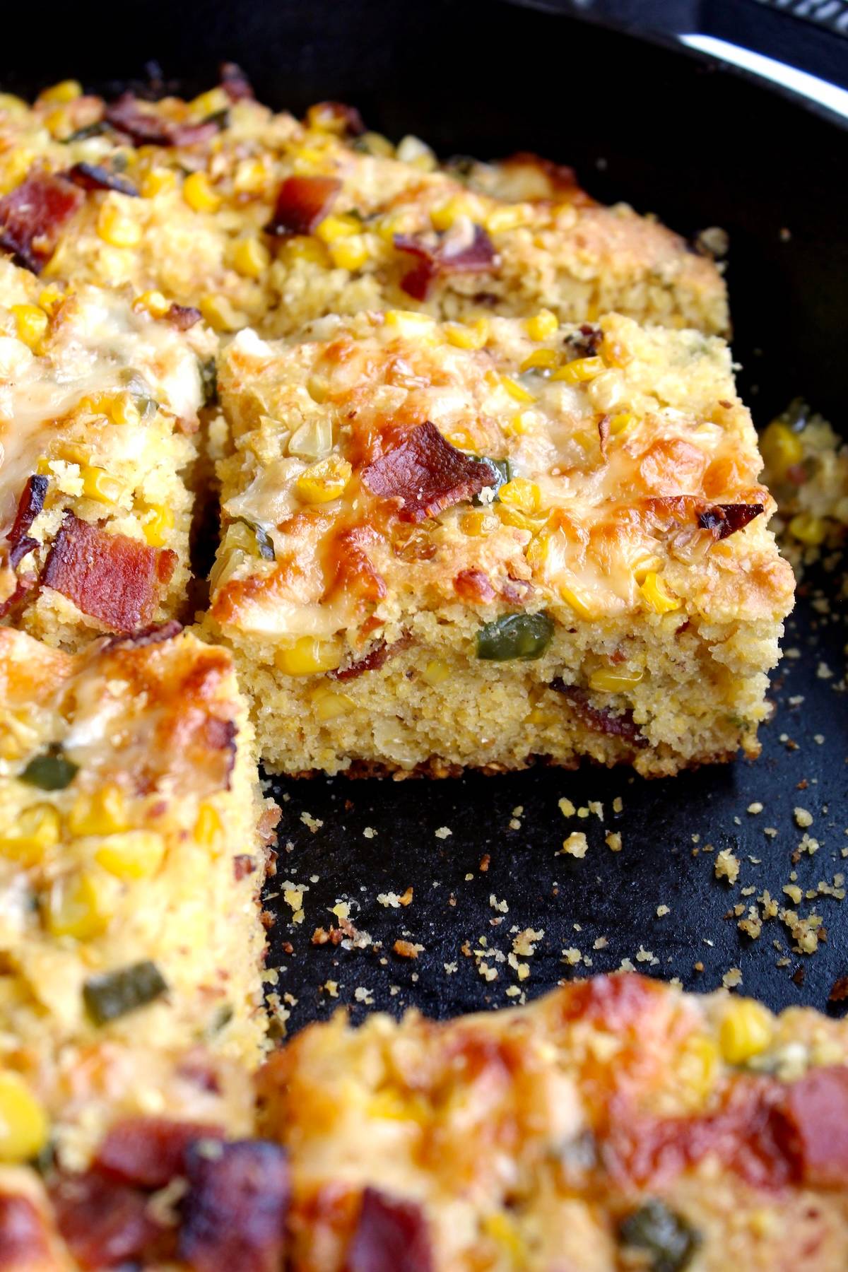 pieces of skillet jalapeno bacon cornbread in a cast iron pan