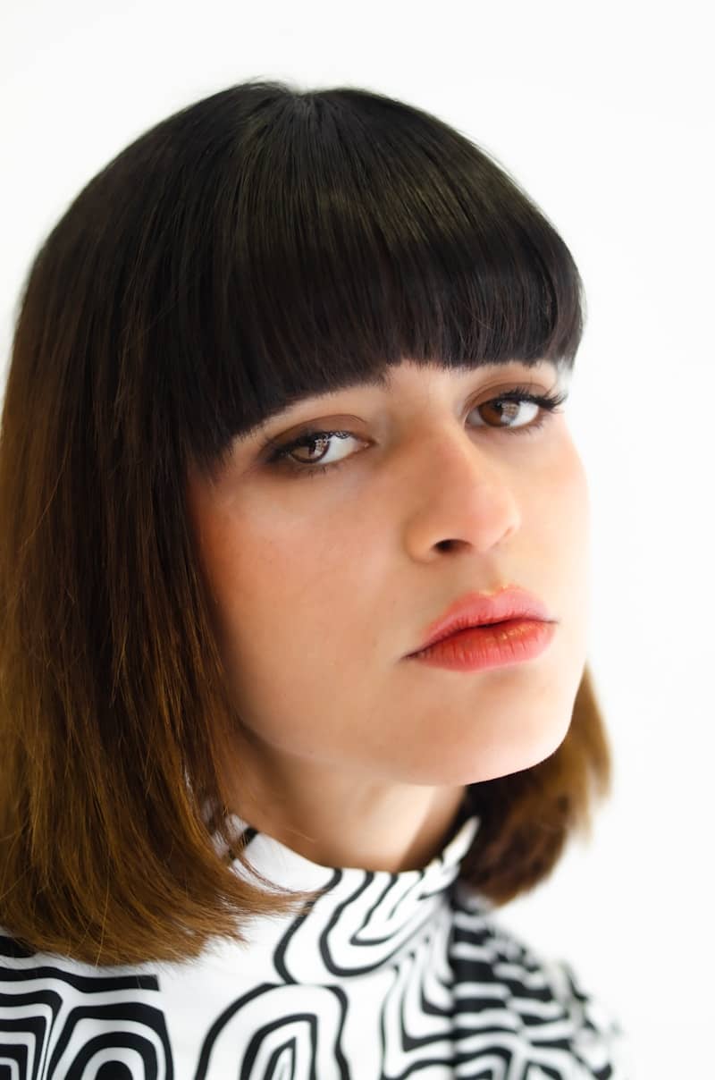 Close-up of a woman with dark bob haircut and bangs.