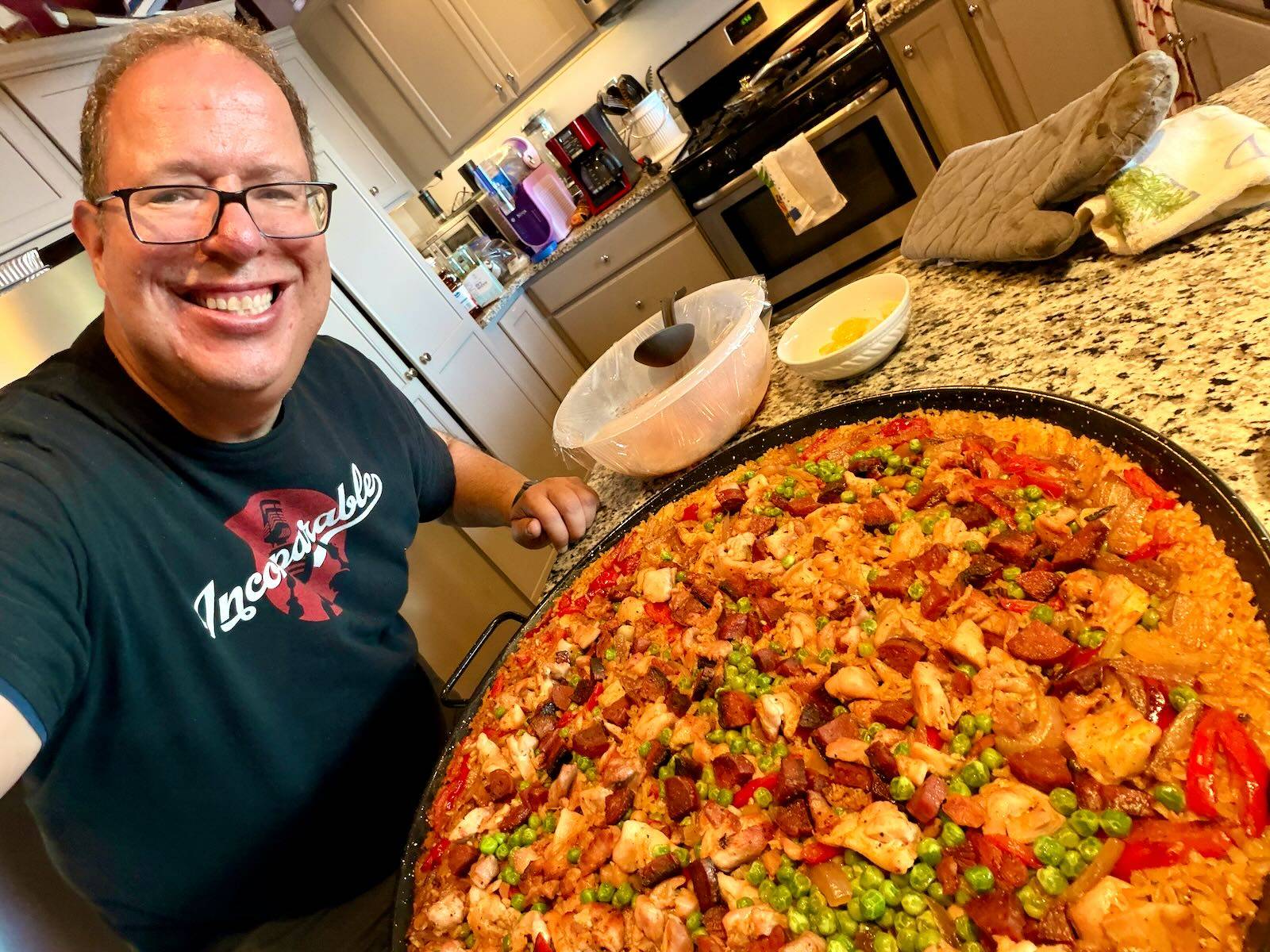 Mike with a pan of paella in a messy kitchen