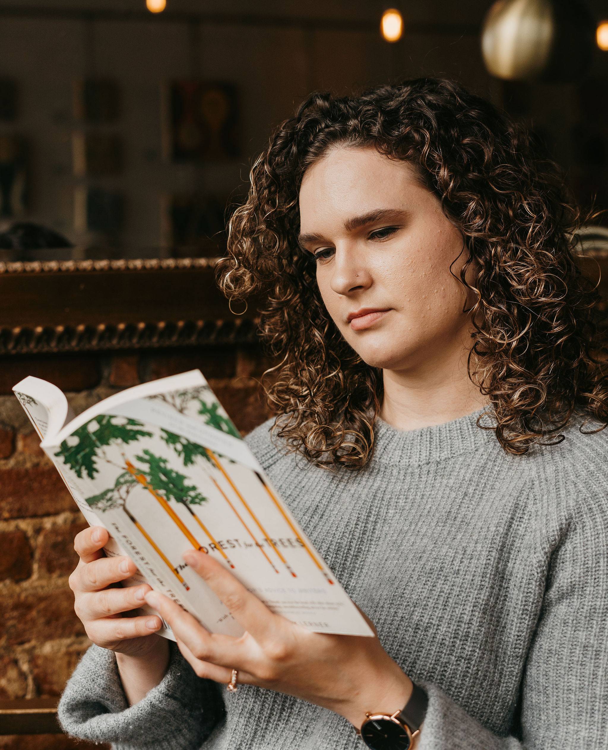 A women with brown curly hair reads a book