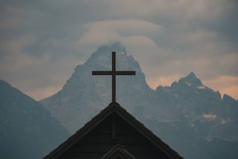 Cross atop church against misty mountains