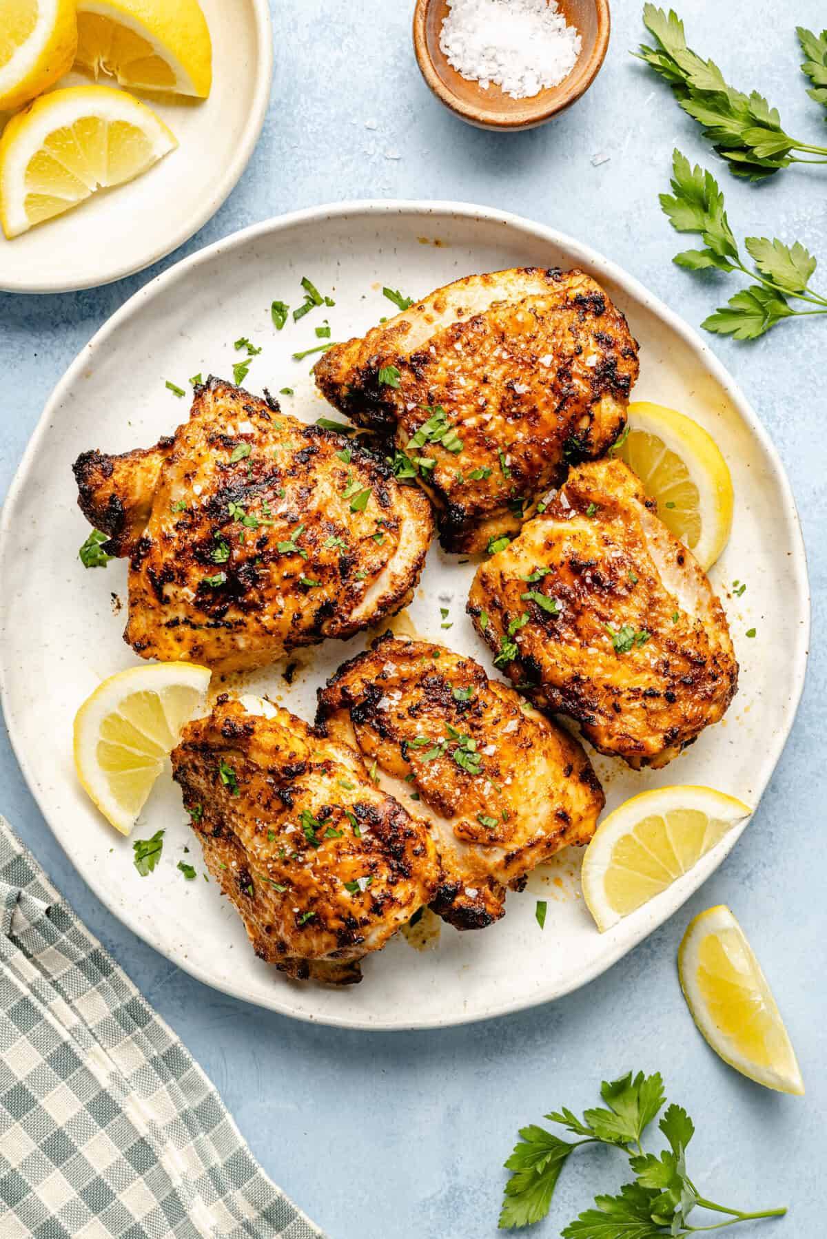 air fryer chicken thighs on plate with lemon slices