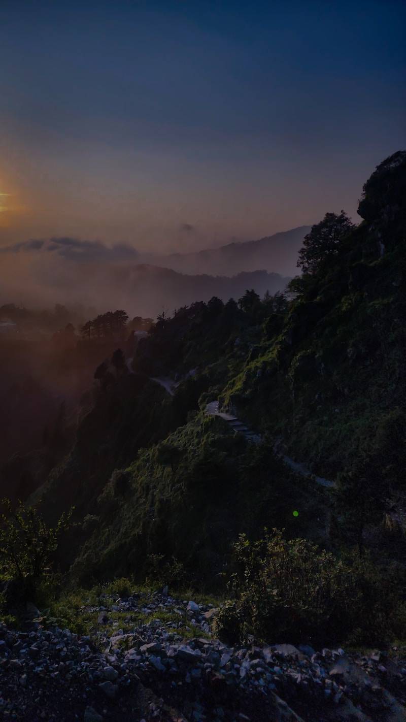 The sun is setting over the mountains in the fog