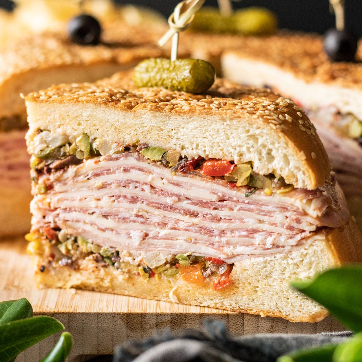large slice of muffaletta sandwich on a cutting board.