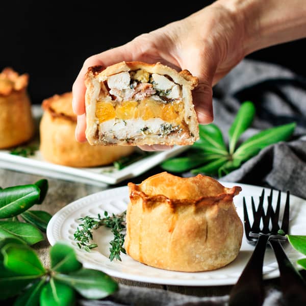 holding half of a chicken, bacon, and apricot pie.