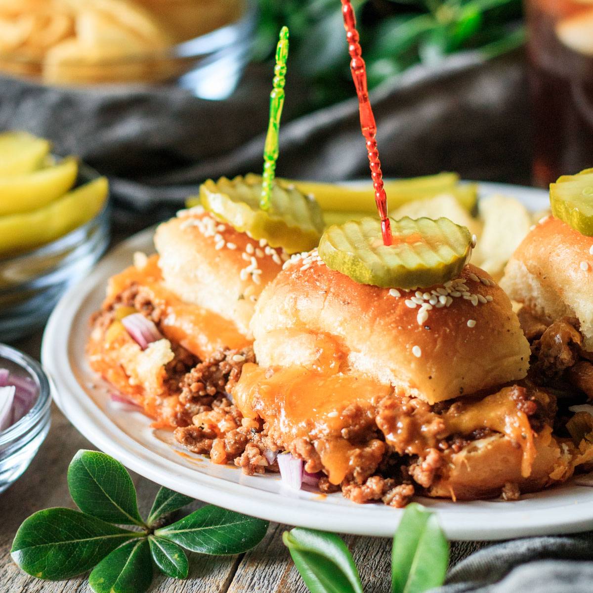 three sloppy joe sliders on a white plate.
