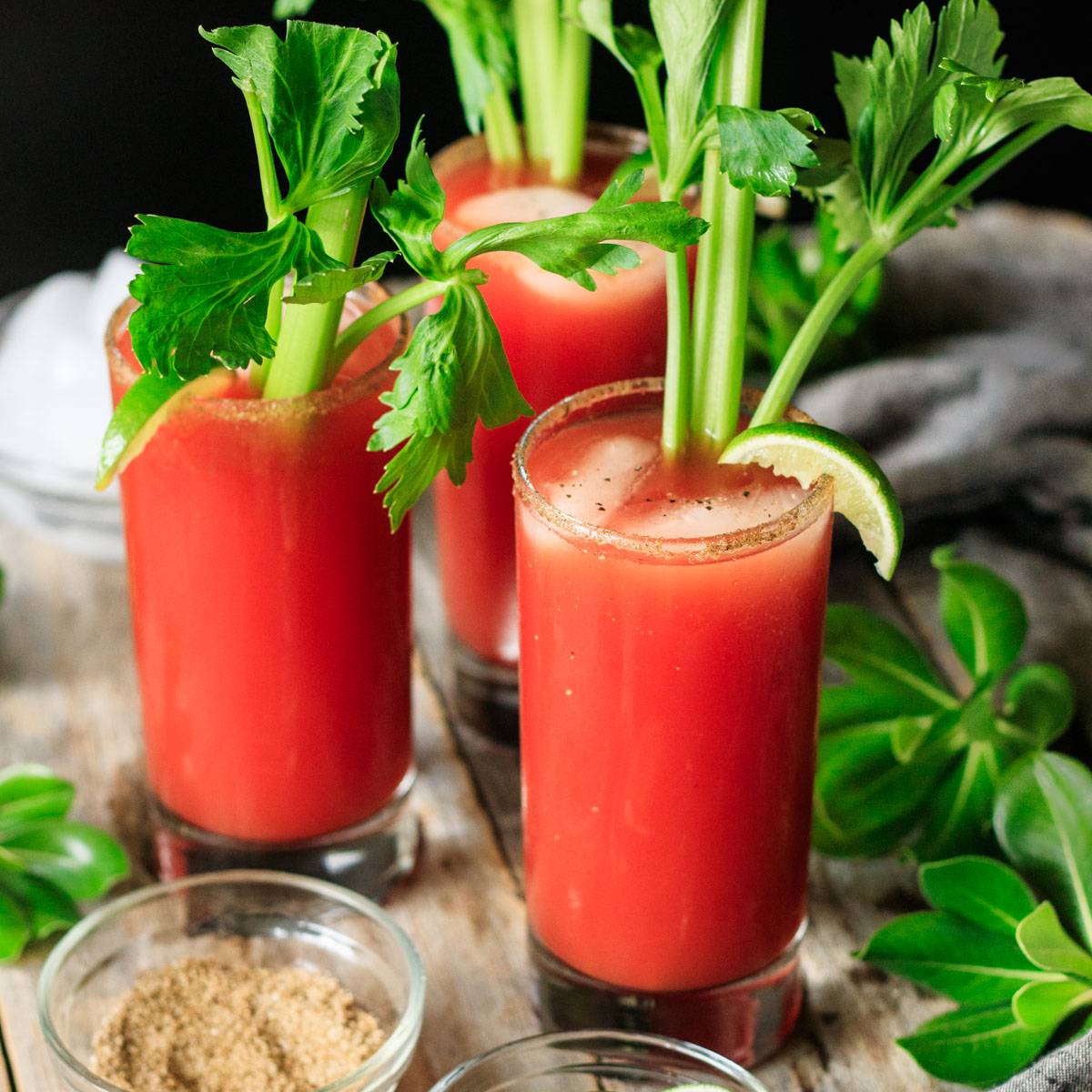 three tall glasses of Caesar mocktail with celery stalks.