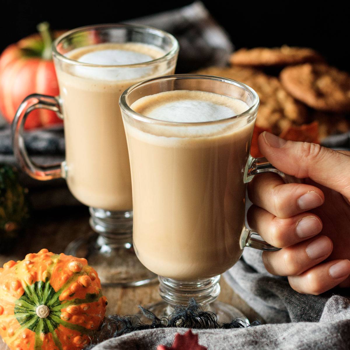 holding a glass mug of Starbucks flat white.