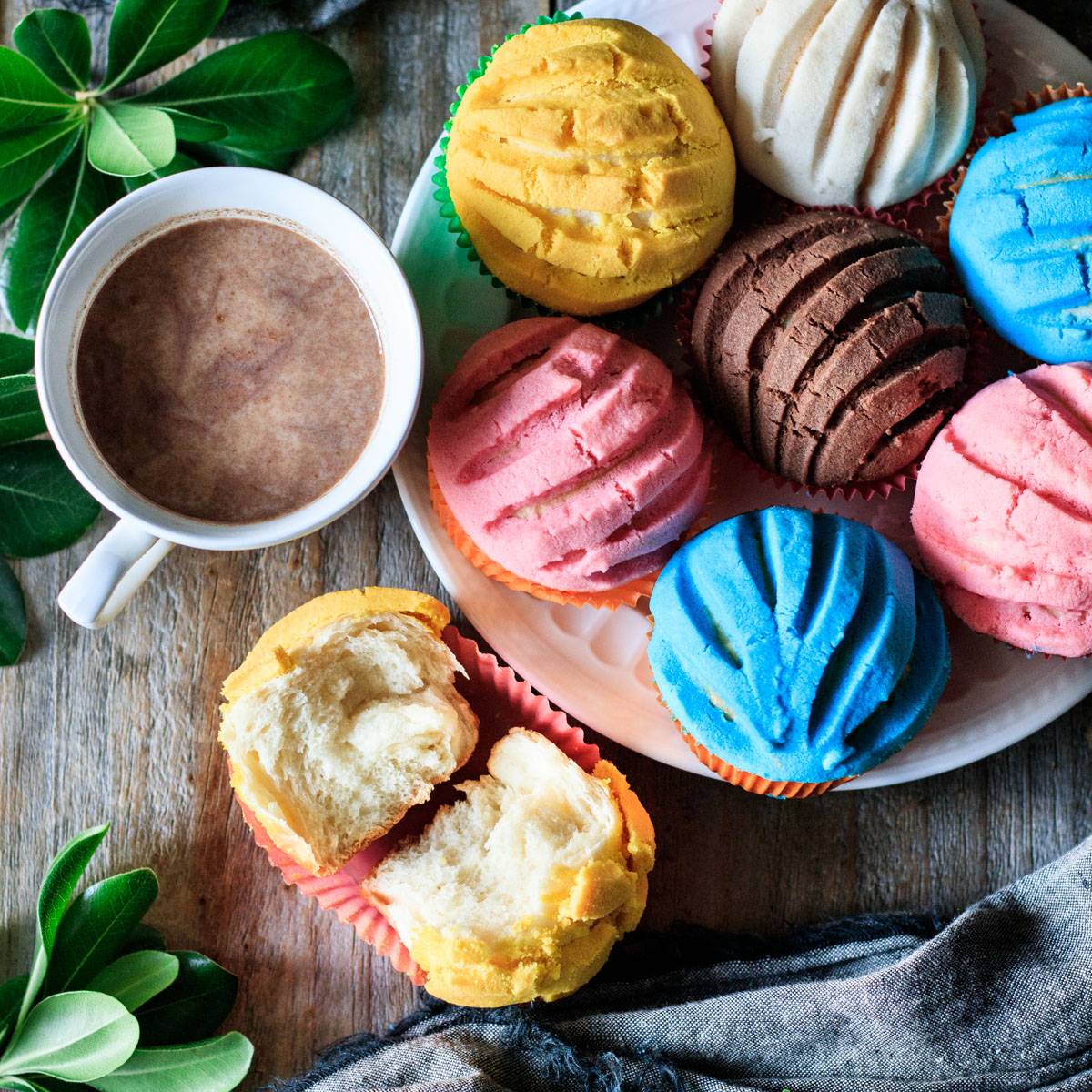 plate of colorful manteconchas with a cup of hot chocolate.