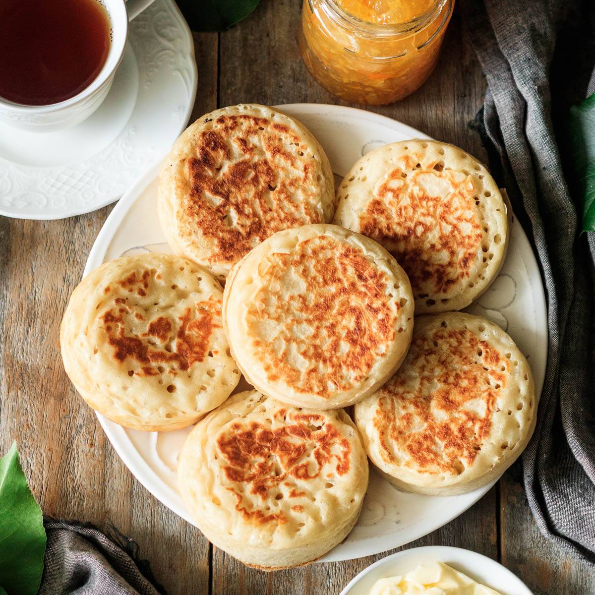 white plate of crumpets with a cup of tea.