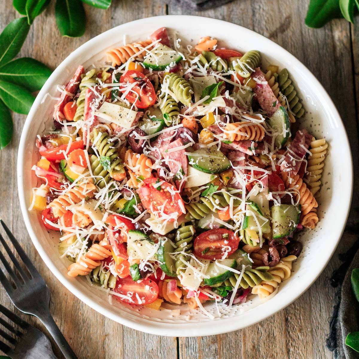 white bowl of Italian pasta salad with two forks.