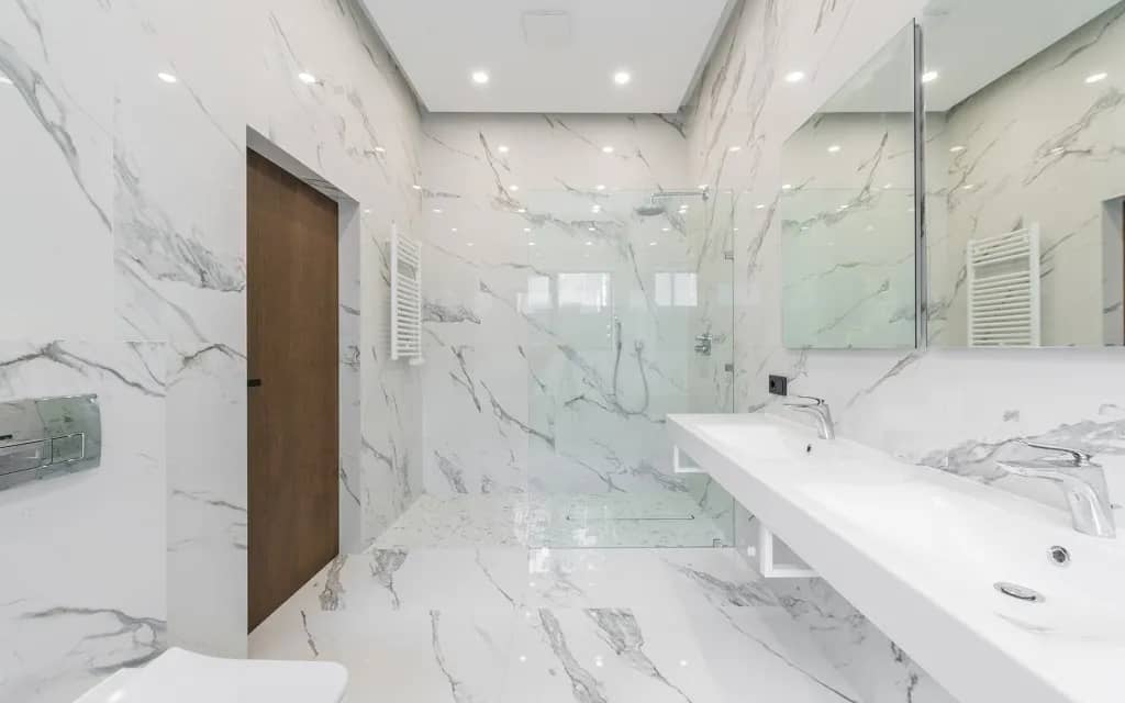 A large accessible bathroom with floating vanity and zero-threshold shower in white marble