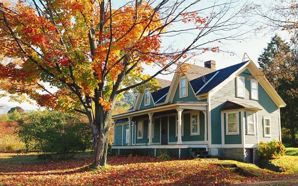 Charming blue house surrounded by autumn foliage