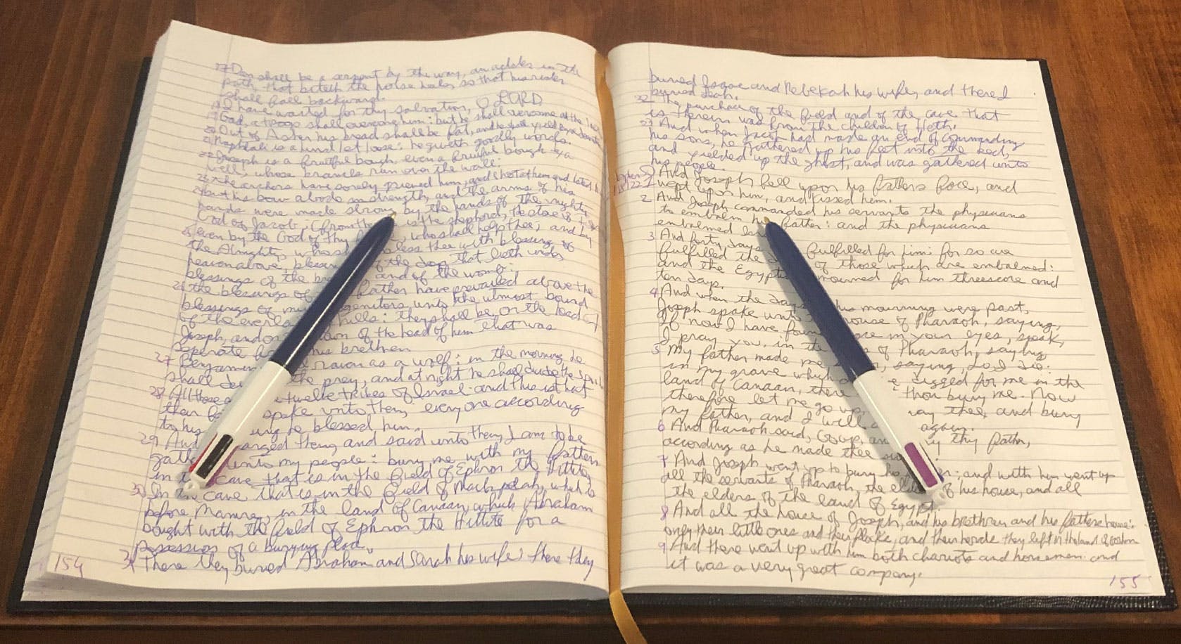 A notebook with a pen lying on it with scripture copied out by hand