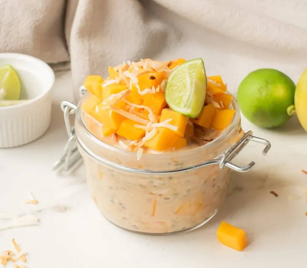 Close up of mango coconut chia overnight oats with toppings in a jar.