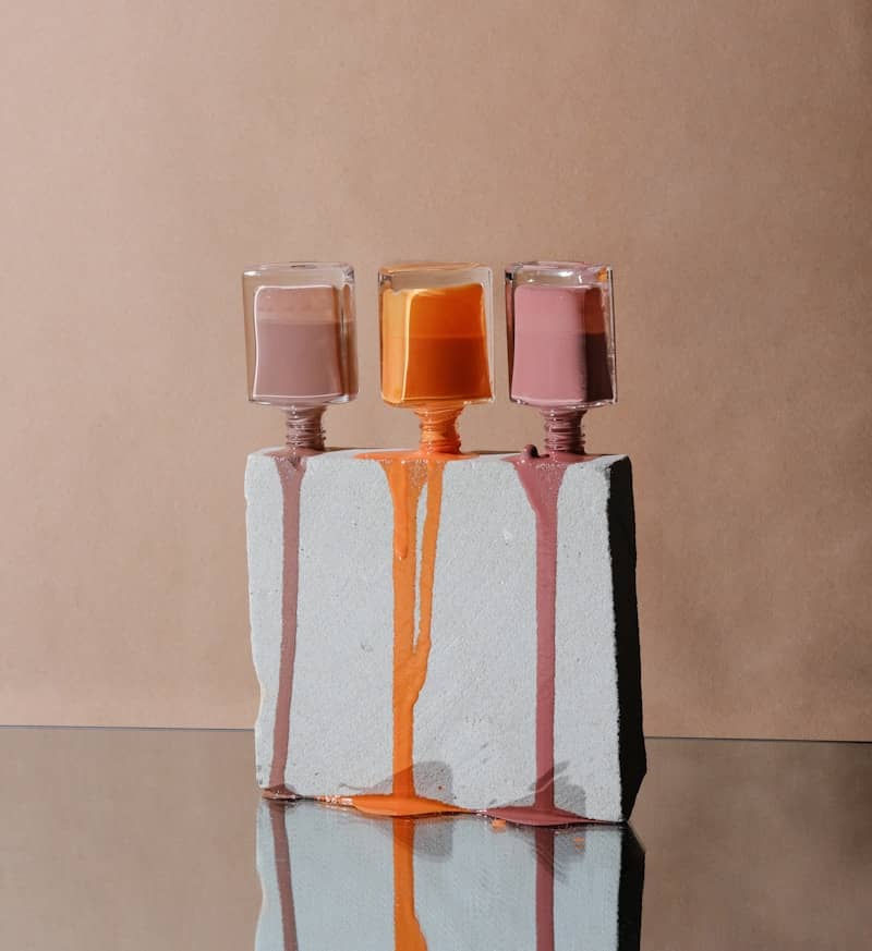 Three bottles of nail polish dripping onto stone.