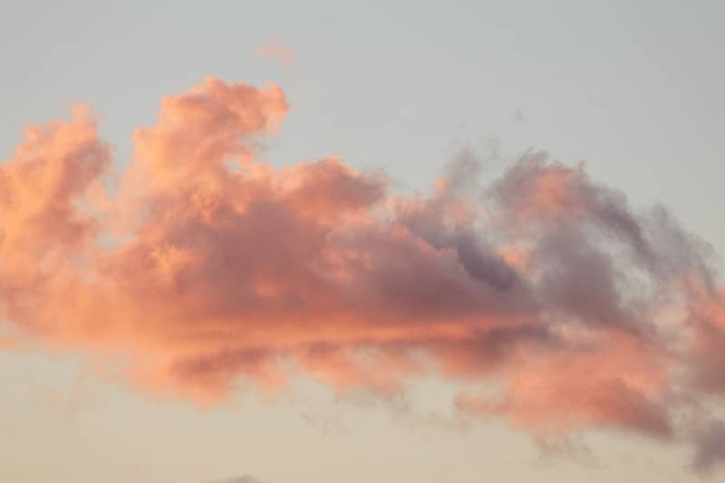 Pink and orange clouds against a pale sky at sunset.