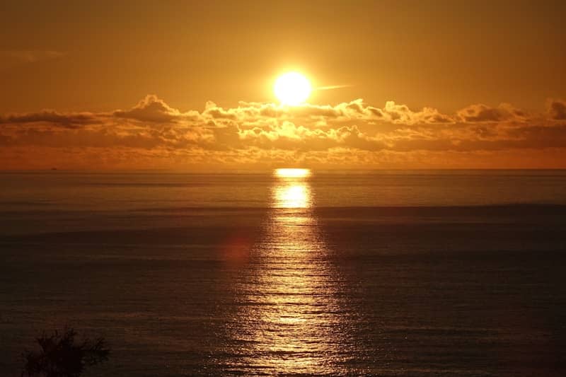 Golden sunset over the ocean with sun reflecting on water.