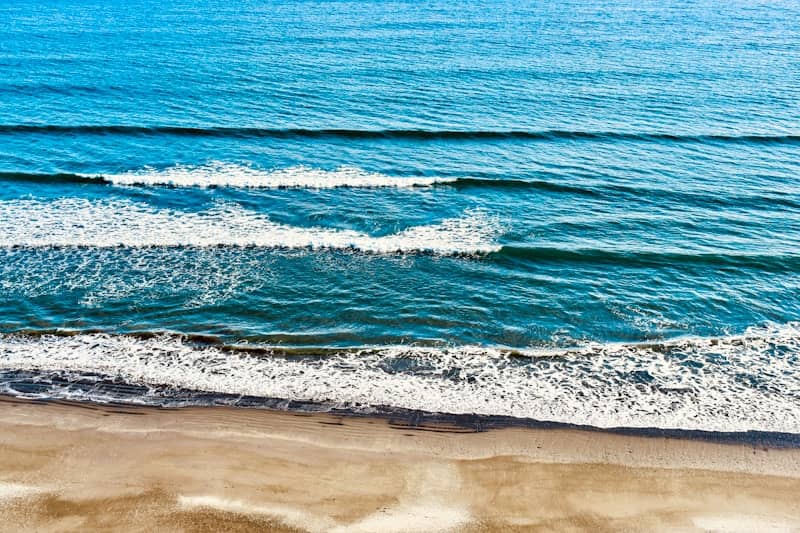Blue ocean waves breaking on a sandy beach.