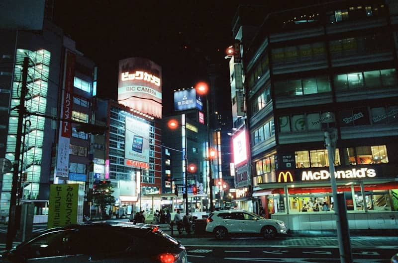 Busy city street at night with bright neon signs.