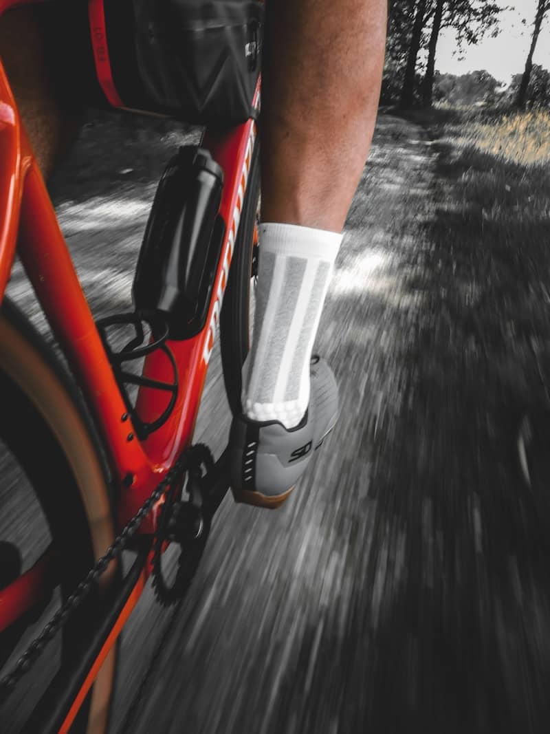 Red bicycle and cyclist's leg in motion on a trail.