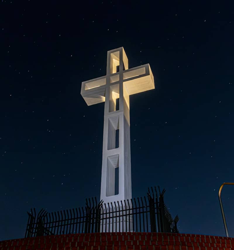 A tall white cross illuminated at night