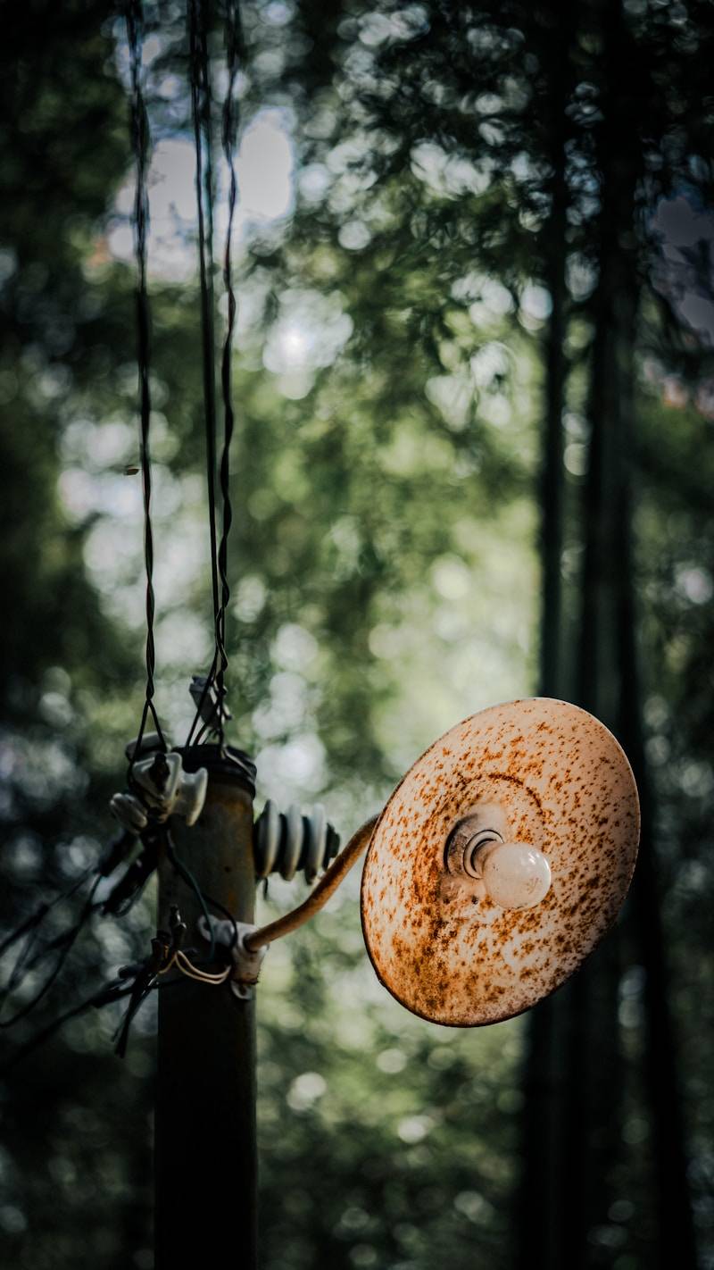 Rusty old street lamp hangs from pole with wires.