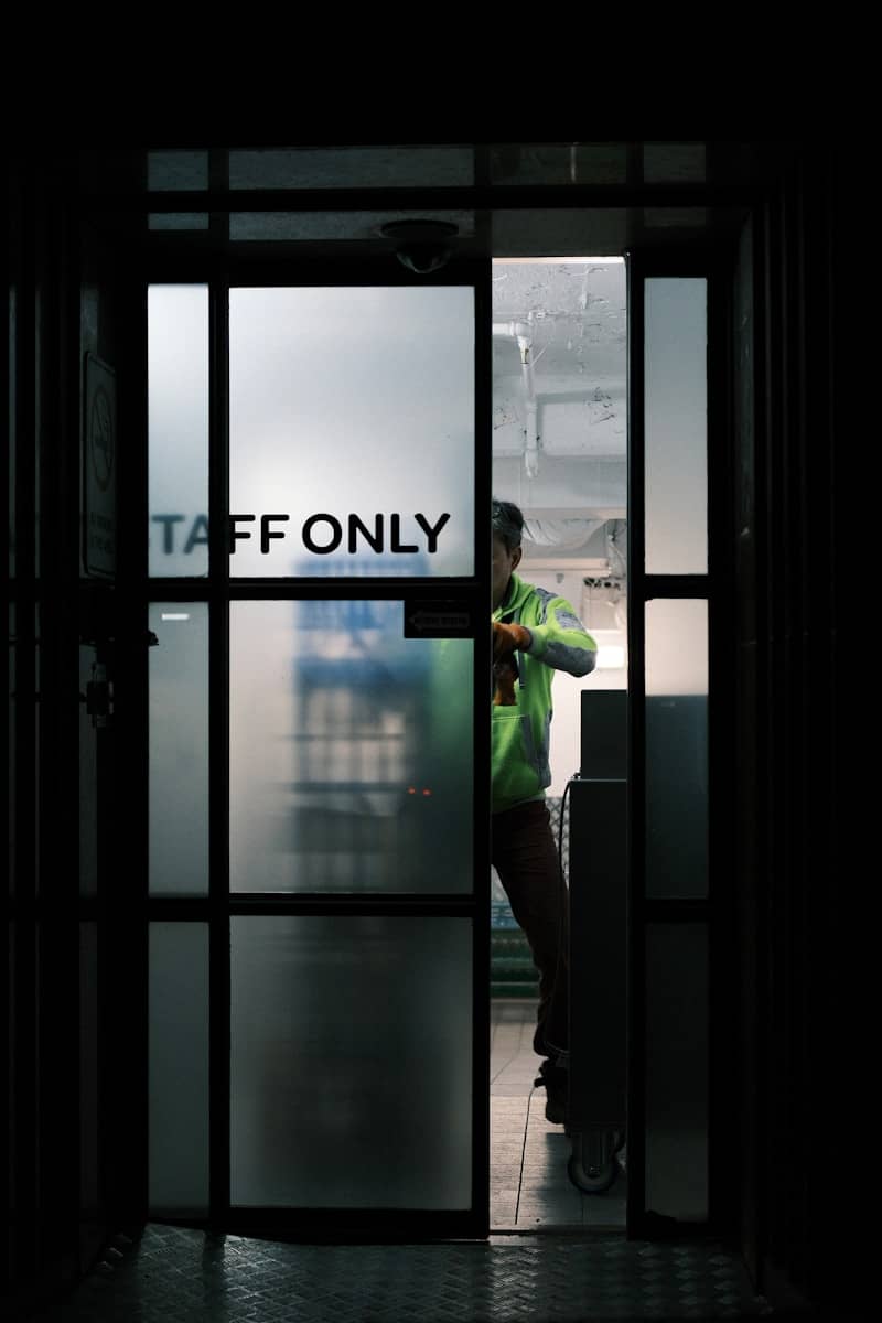 A person in green through a frosted "staff only" door.