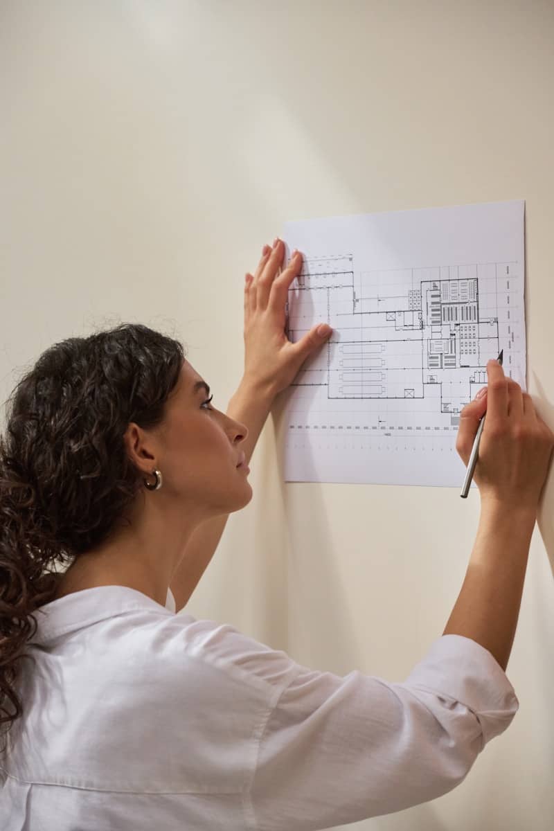 An architect examines a blueprint on the wall.
