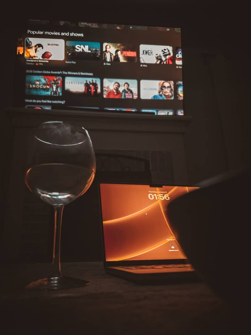 A glass of wine sitting next to a laptop computer