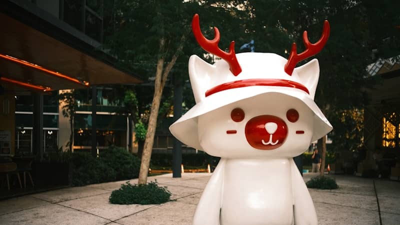 White cartoon character with antlers and hat outdoors.