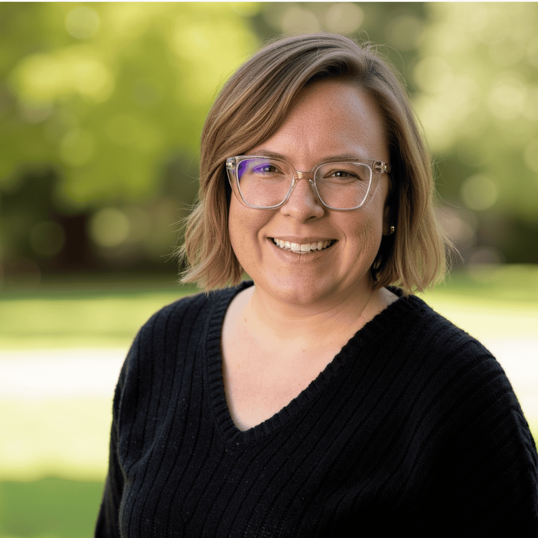 ```plaintext
A promotional flyer featuring a smiling woman with glasses standing outdoors in front of a blurred background of trees and grass. Below her photograph, text introduces Dr. Elizabeth "Liz" Polinsky as a certified Emotionally Focused Therapy supervisor and therapist for individuals, couples, and families. She is the founder of Communicate & Connect Counseling. Her interests include swing dancing, making wine, and hosting a podcast for military relationships. Two logos are at the bottom: one for the APA and one labeled GPA.
```