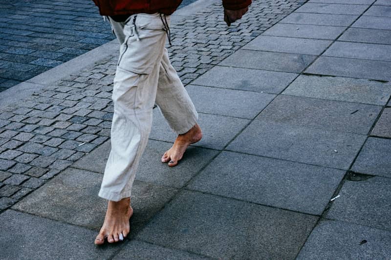 Barefoot person walks on a paved sidewalk