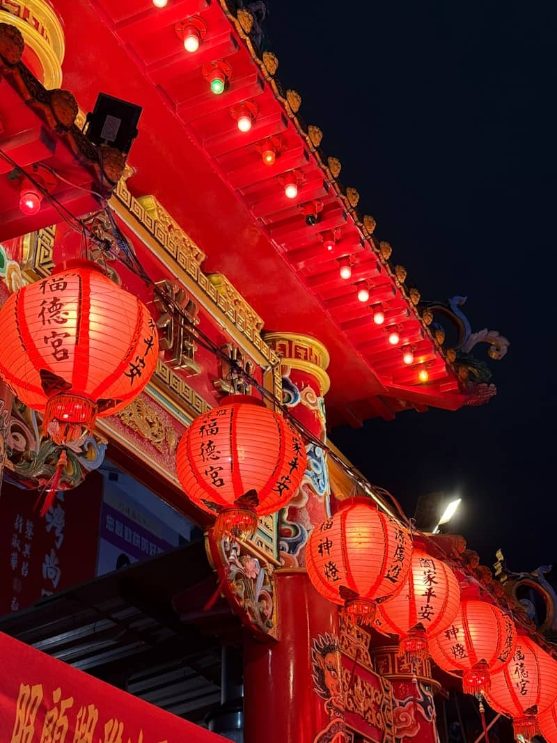 Red lanterns illuminate a traditional temple at night.