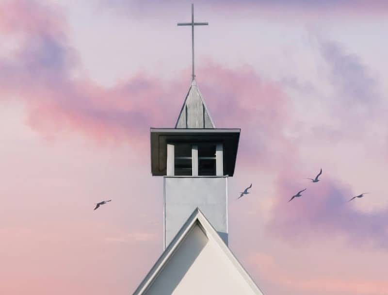 White church steeple against a pastel sky with birds.