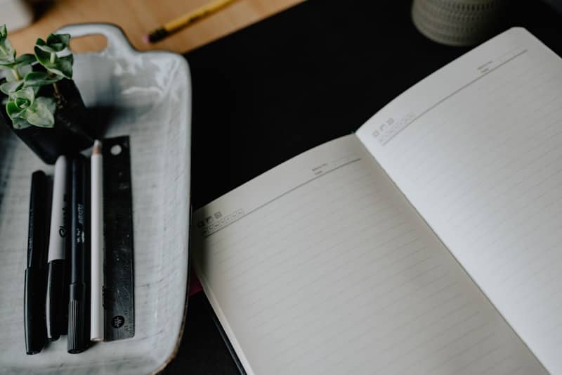 An open notebook and pens on a desk.