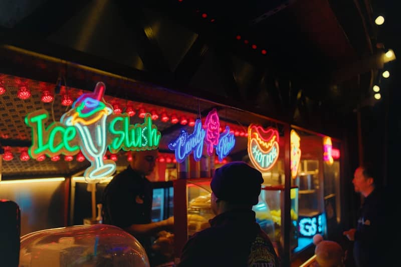 Neon signs for ice slush and desserts at a bar