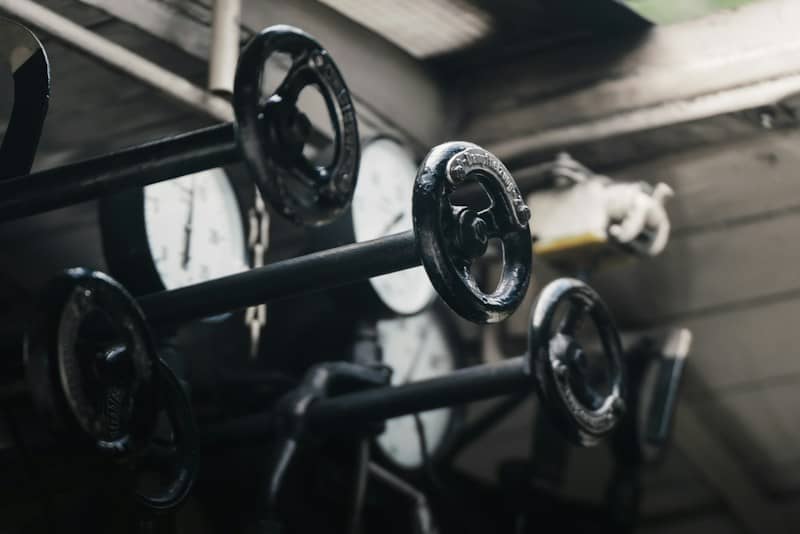 Black metal handwheels and circular pressure gauges in an industrial setting