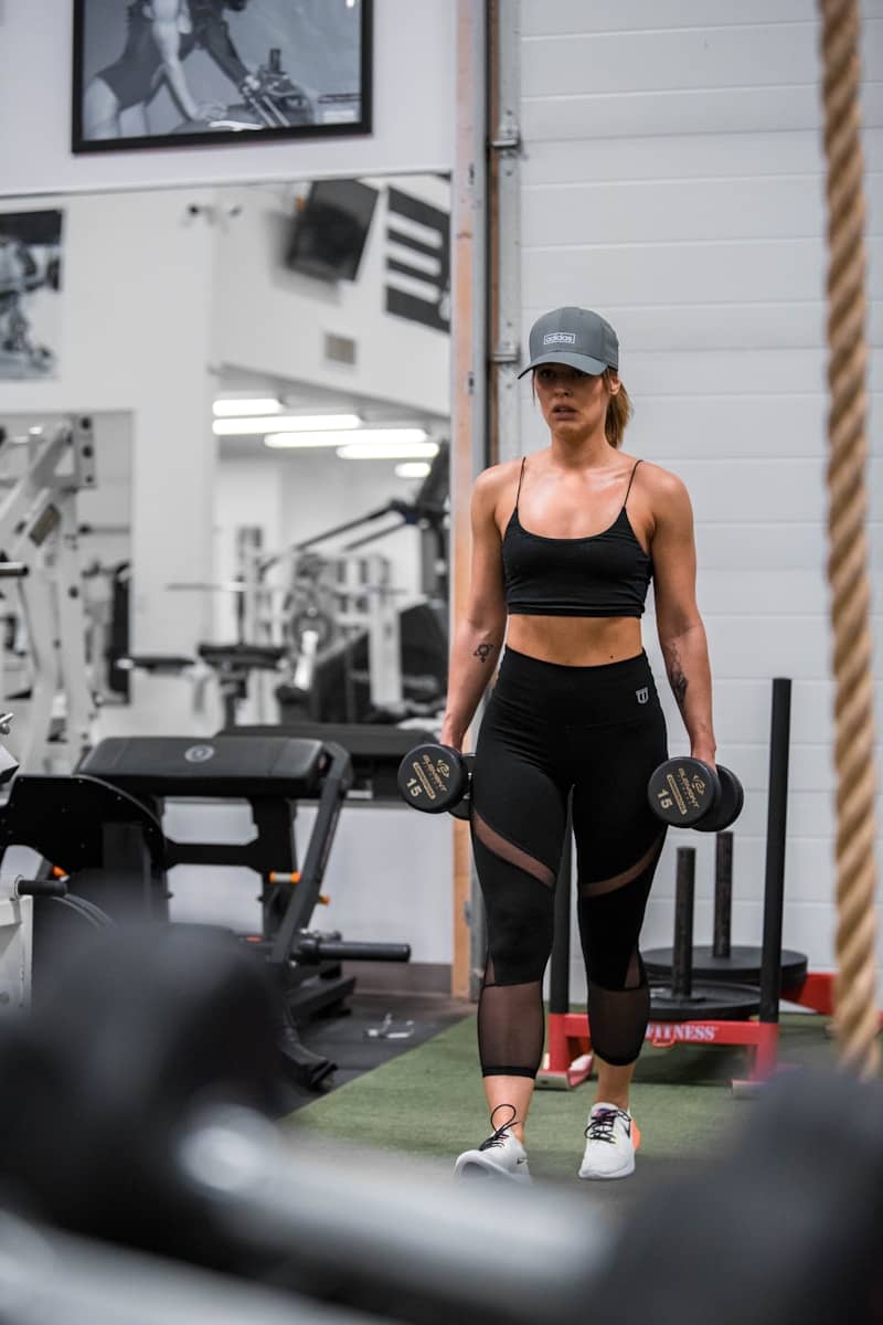 Athletic woman walking in gym with dumbbells