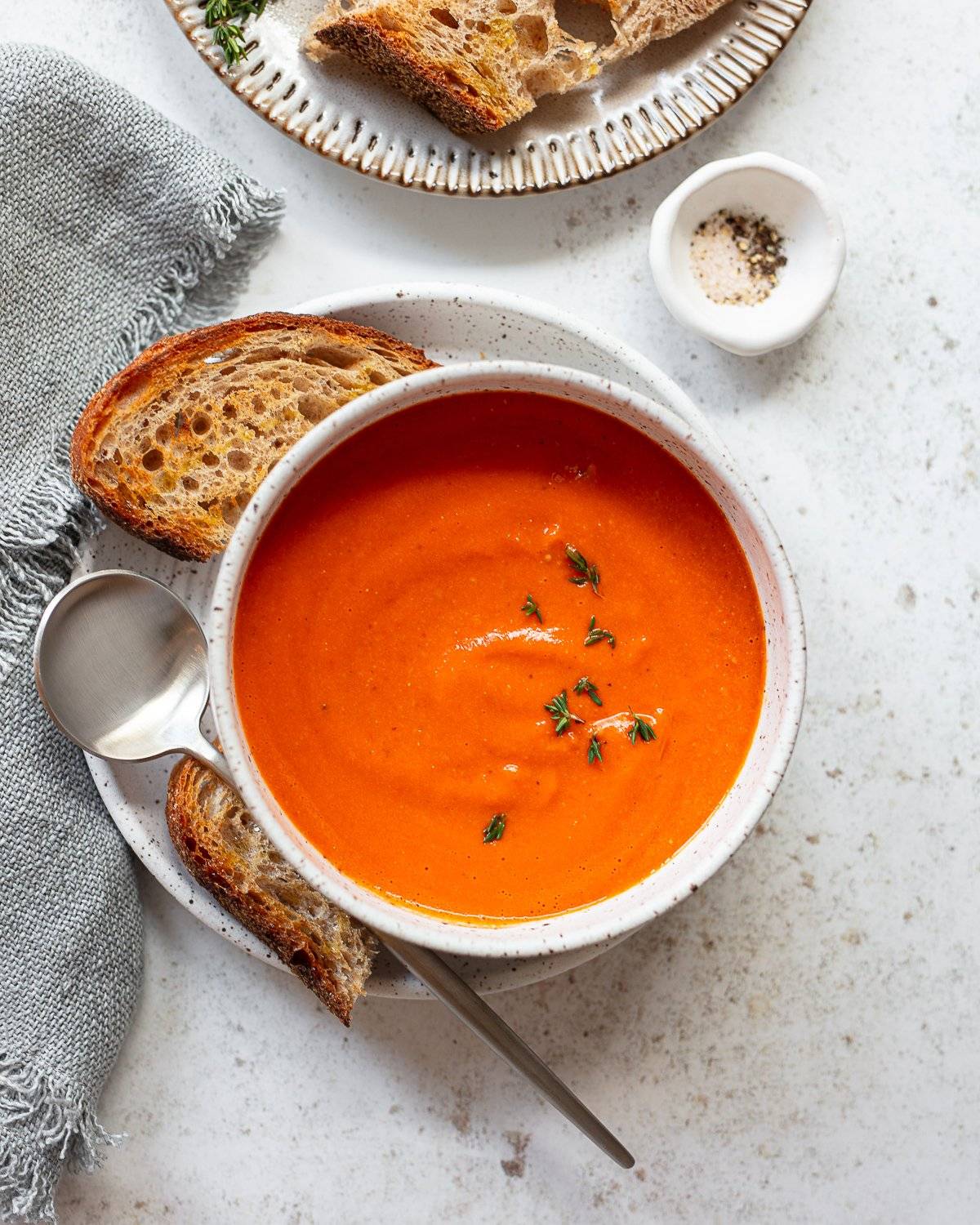 A bowl of creamy tomato soup with toast on the side.