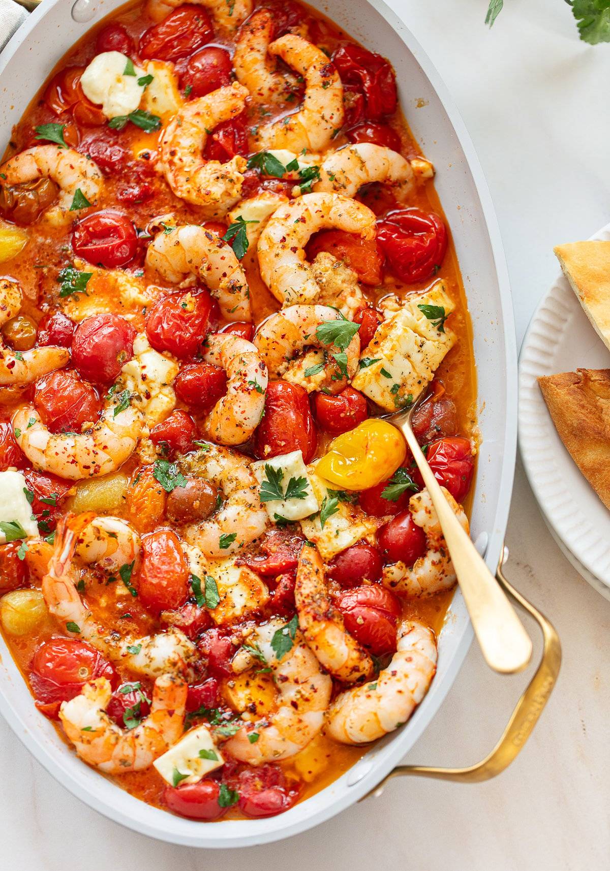 Baked shrimp, tomatoes and feta cheese in an oval pan.