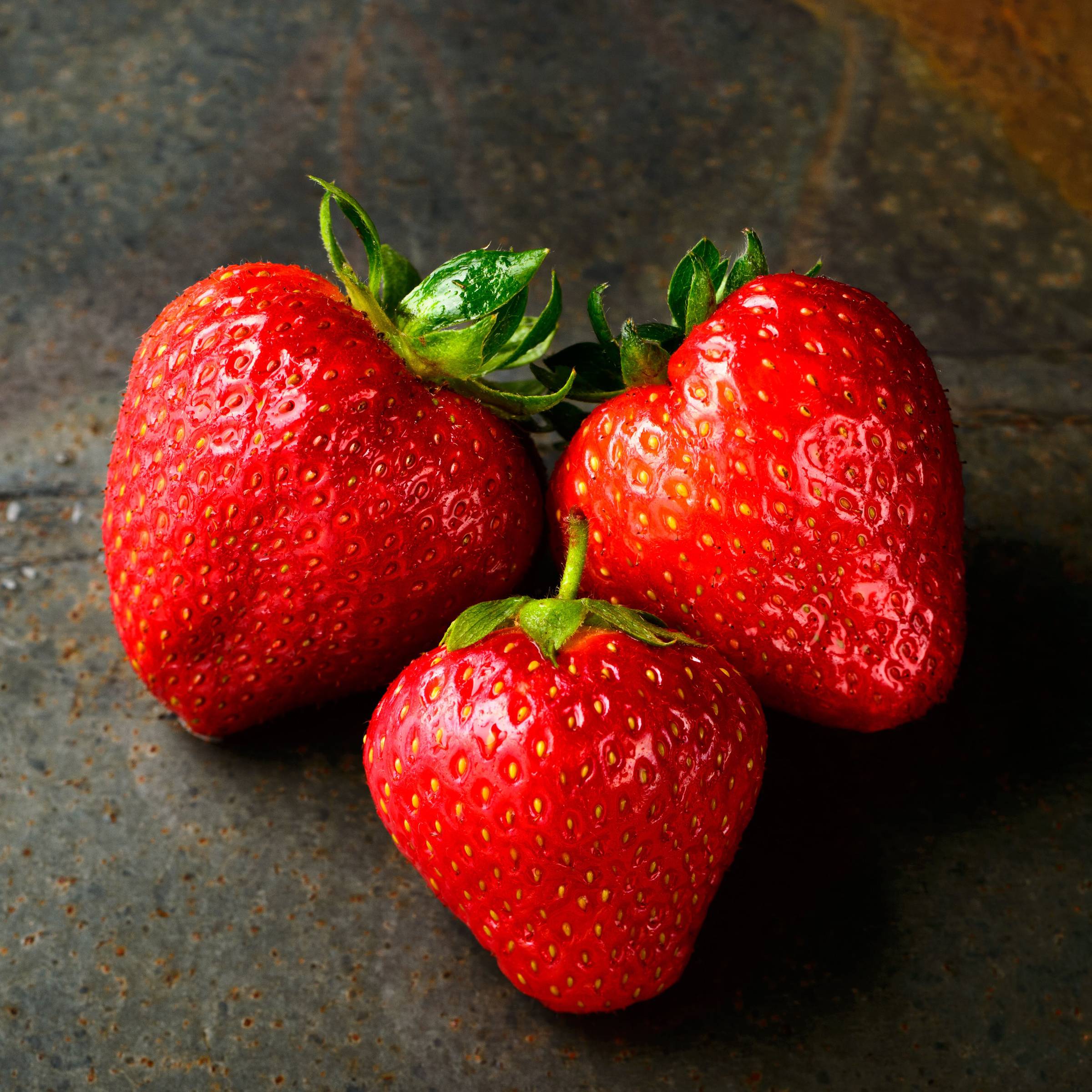 three ripe strawberries on wood 