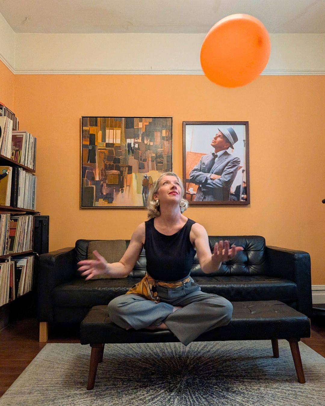 blonde woman in orange room waiting to catch an orange balloon