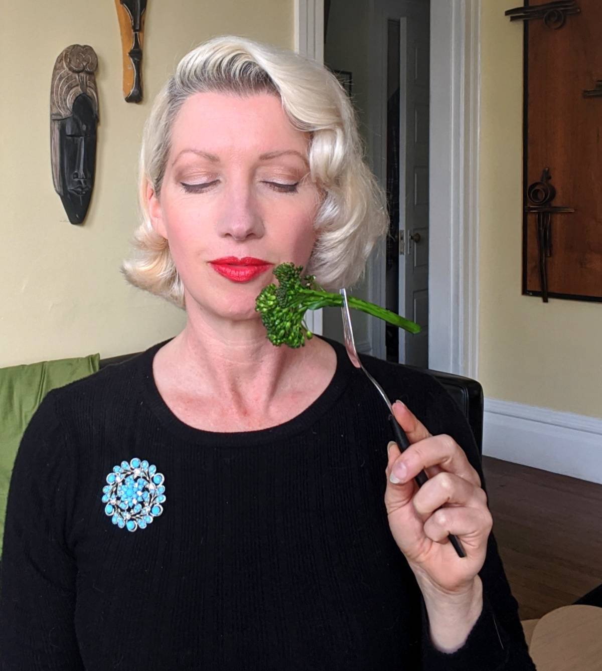 woman holding broccoli up to her red lips