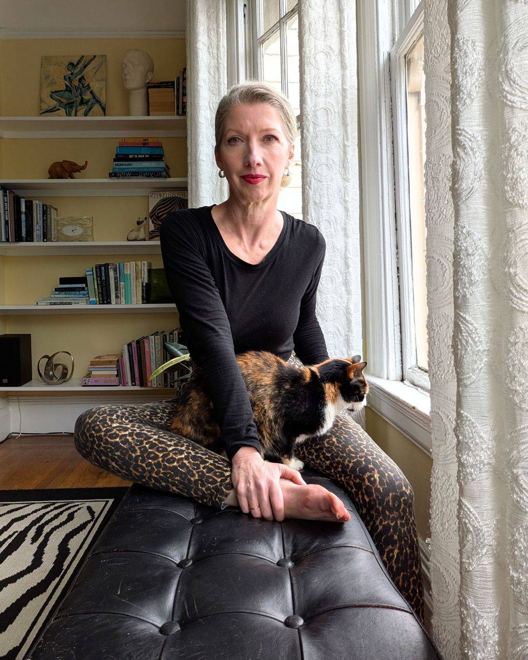 woman in leopard pants with calico cat on her lap