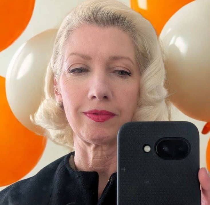 woman looking at phone with white and orange balloons behind her